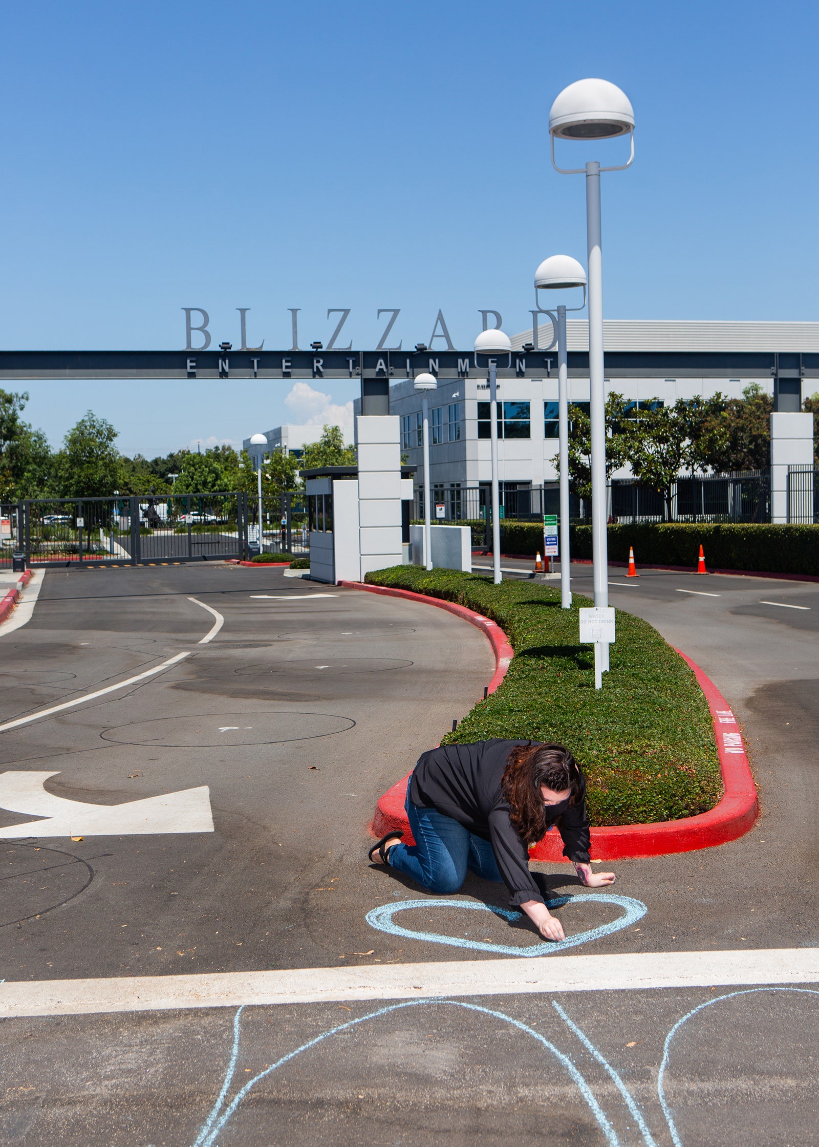 woman chalking a blue heart in front of entrance to blizzard campus